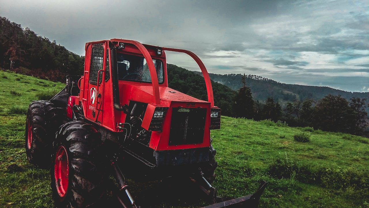A red tractor in a lush green field under a cloudy sky, showcasing rural farming life.